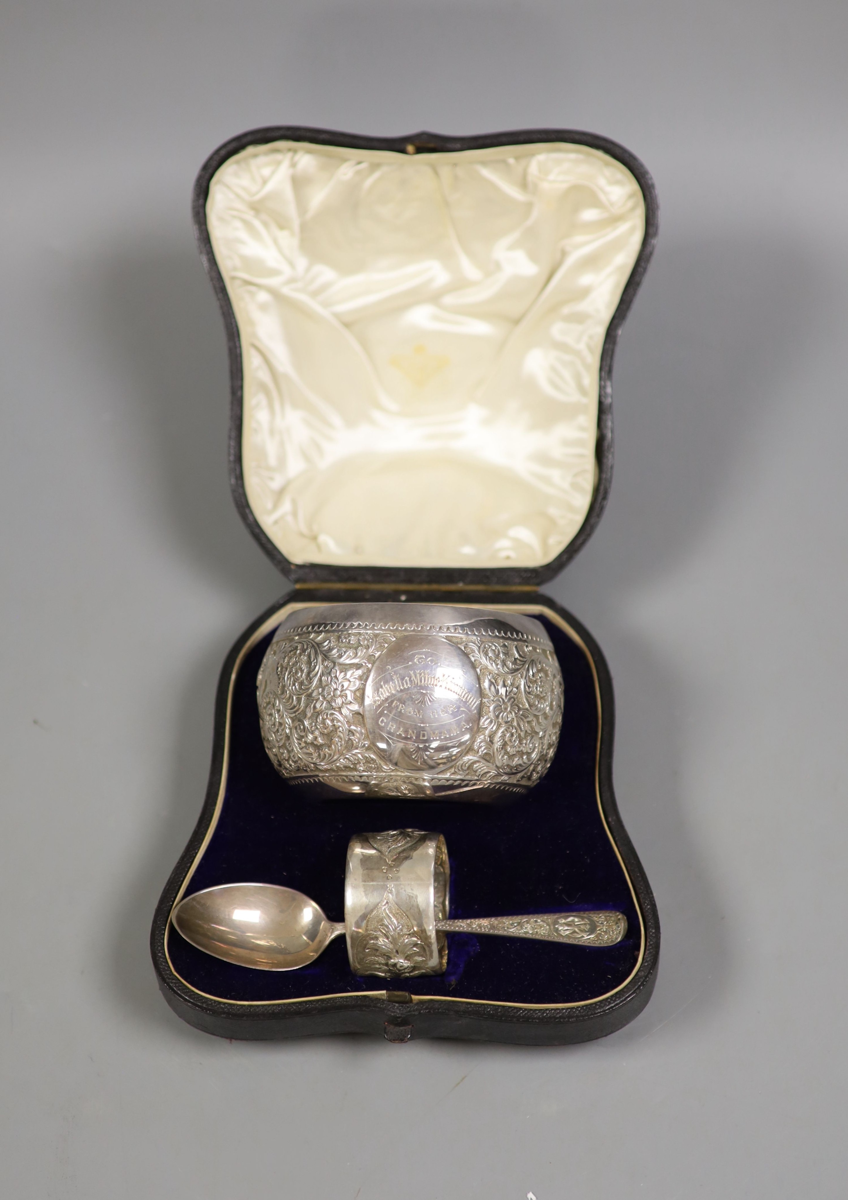 A Victorian cased matched embossed silver christening trio, comprising , bowl, napkin ring and fork, bowl, Sheffield, 1889, 10.3cm, 5.5oz.